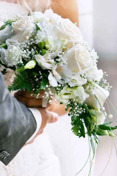 Primer plano de las manos del novio y la novia con ramo de boda — Foto de Stock