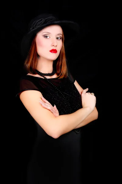 Элегантная женщина в черном платье и шляпе над черным — стоковое фото