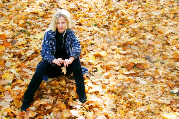 Young beautifu woman sitting on autumn leaves — Stock Photo, Image