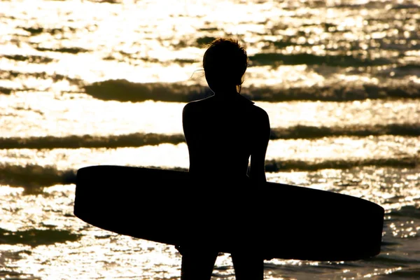 Silhueta de menina com tábua de pipa no pôr do sol mar — Fotografia de Stock