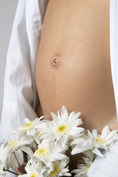 Woman's belly and white flowers — Stock Photo, Image