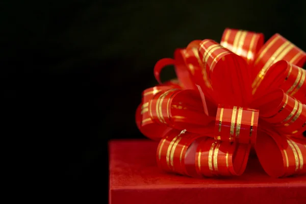 Red ribbon and gift box over black background — Stock Photo, Image