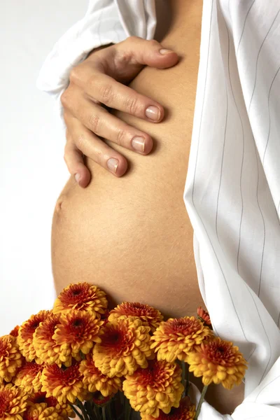 Woman belly and red flowers — Stock Photo, Image