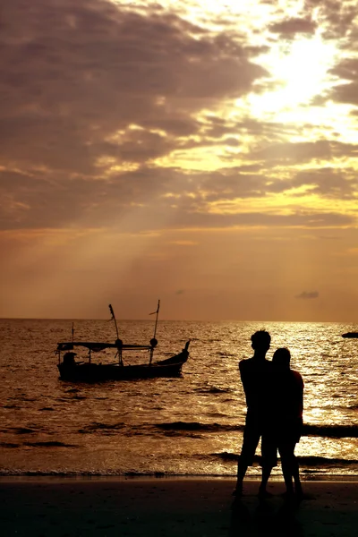 Älskande par på stranden vid solnedgången — Stockfoto