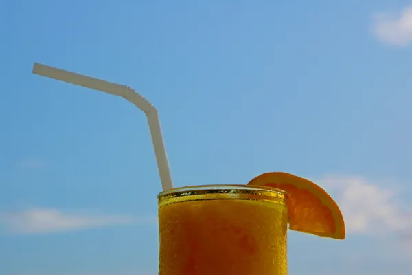 Glass of juice against blue sky — Stock Photo, Image