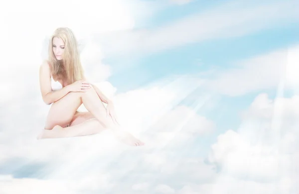 Alone angel girl in sun rays sitting on clouds — Stock Photo, Image