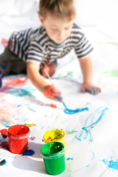 Young boy painting, focus on cans — Stock Photo, Image