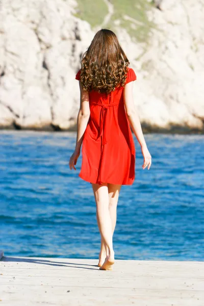 Молодая девушка в красном платье на море Лицензионные Стоковые Изображения
