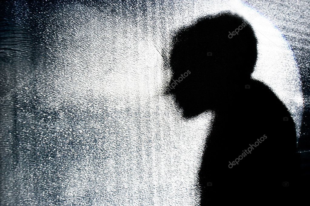 person's silhouette behind textured glass wall