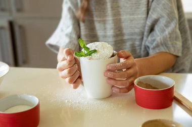 Çocuklar yumurta tutuyor, beyaz mutfak masasında malzemeler pişiriyor, çocuklarla evde pişiriyor, kupa hazırlıyor.