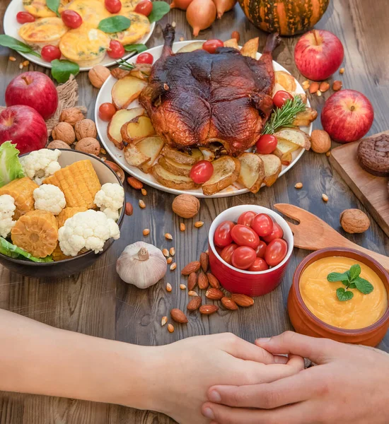 Lidé drží za ruce, díkůvzdání večeře podávané na dřevěném pozadí, vařené krocana nebo kuře se zeleninou, listopadová oslava, koncept díkůvzdání plnosti a sounáležitosti — Stock fotografie