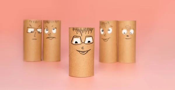 Una persona de pie frente a los demás, grupo de personajes hechos de rollos de papel higiénico con la cara pintada expresando felicidad o satisfacción sobre el fondo rosa, concepto de grupo de emociones, bricolaje — Foto de Stock