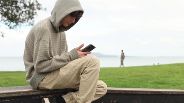 Teenager dreng med mobiltelefon på naturlig baggrund, mobil kommunikation, digital teknologi – Stock-video