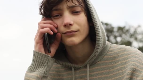 Teenager boy with cell phone on natural background, mobile communication, digital technology — Stock Video