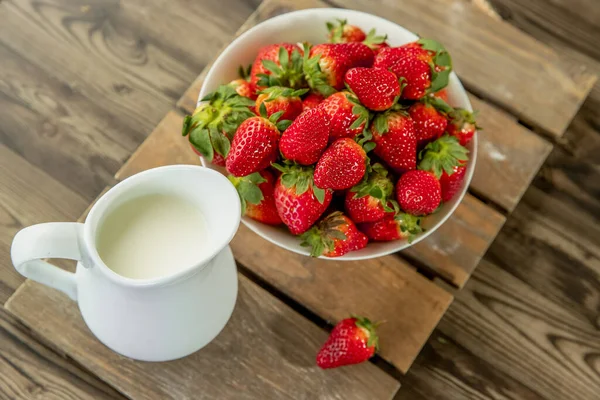 Świeżo zebrane organiczne truskawki i mleko na drewnianym stole naturalne tło, wsi, zdrowe odżywianie — Zdjęcie stockowe