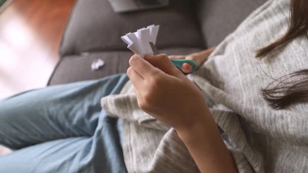 Νεαρή κοπέλα κόβοντας μια νιφάδα χιονιού από λευκό χαρτί με ψαλίδι στο σπίτι, πρώιμη εκπαίδευση, χειροτεχνία και τέχνη έννοια — Αρχείο Βίντεο