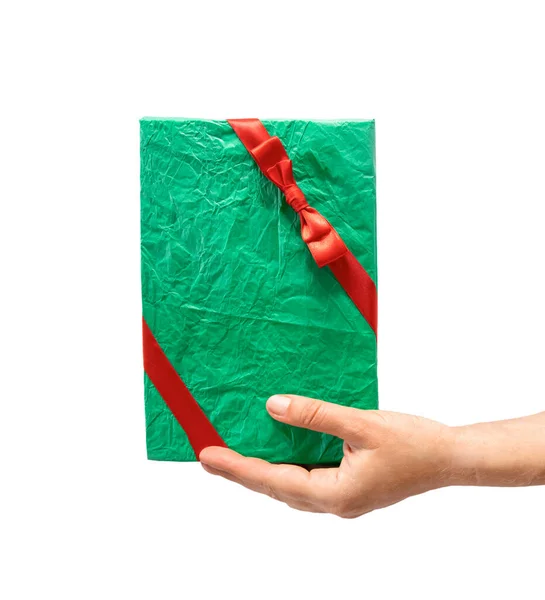 Hand holding gift box wrapped in green recycled paper with red ribbon isolated over white background, promo, discount concept, Christmas sales, copy space — Stock Photo, Image