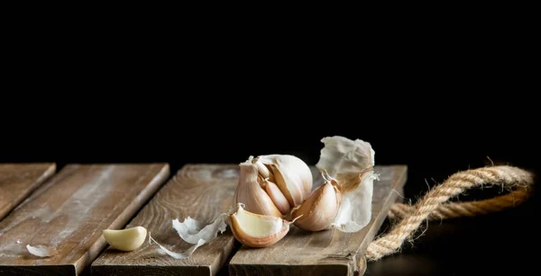 Fresh organic garlic over black background, full heads, cloves and peels, cooking ingredients — Stock Photo, Image