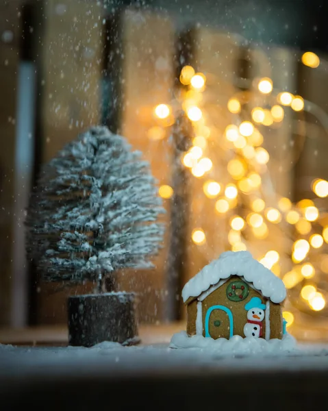 Gingerbread house and Christmas tree over wooden background with blurred lights, Christmas postcard, xmas mood, festive vibes — Stock Photo, Image