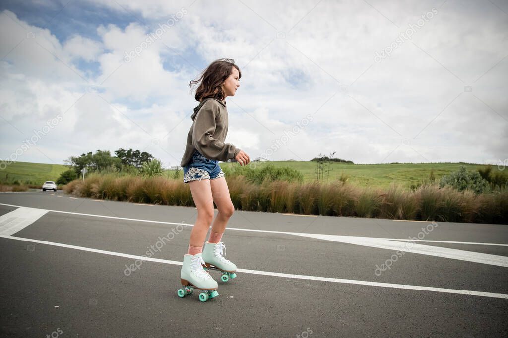 portrait of young child or teen girl roller skating outdoors, firness, wellbeing, active healthy lifestyle. High quality photo
