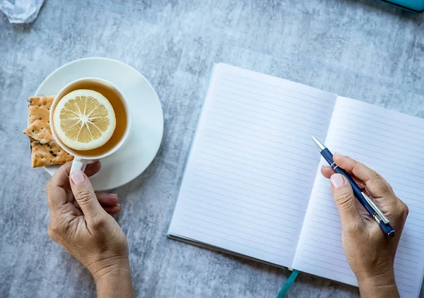 手は平たく灰色の背景に本にスミスを書いてるお茶とフリーランスの仕事のカップ 高品質の写真 — ストック写真