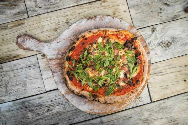 Свежеприготовленная итальянская пицца на деревенском деревянном столе, готовая к обеду — стоковое фото