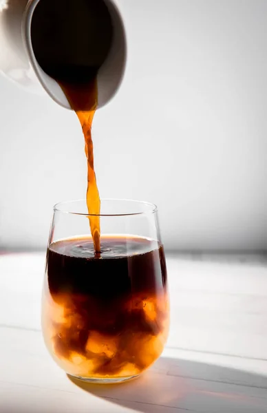 Café esburacado gelado ou congelado em um copo, respingo com gotas, sobre fundo cinza — Fotografia de Stock