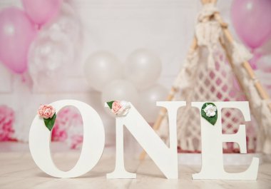 Birinci yaş günü pastası için pembe ve beyaz süsleme balonlarla, kağıt dekorlarla, pasta ve süslemelerle stüdyo fotoğraf çekimi.