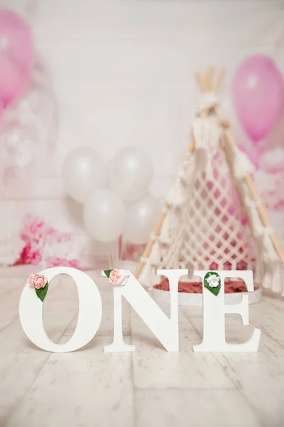 Birinci yaş günü pastası için pembe ve beyaz süsleme balonlarla, kağıt dekorlarla, pasta ve süslemelerle stüdyo fotoğraf çekimi. — Stok fotoğraf