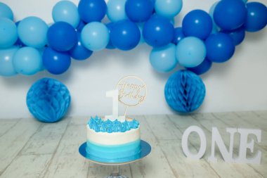 Birinci yaş günü pastası için ince, mavi ve beyaz süsleme balonlar, kağıt dekorlar, pasta ve süslemeler ile stüdyo fotoğraf çekimi. Yüksek kalite fotoğraf