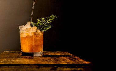 iced tea with crashed ice in a transparent glass isolated over dark black background with space for text or promo, on wooden table top. High quality photo