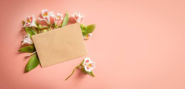 fresh pink flowers in an envelope on pink background with space for text. High quality photo