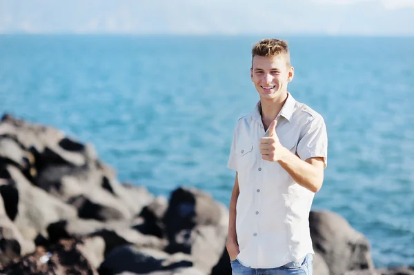 Smiling boy showing thumb up on sea background — Stock Photo, Image