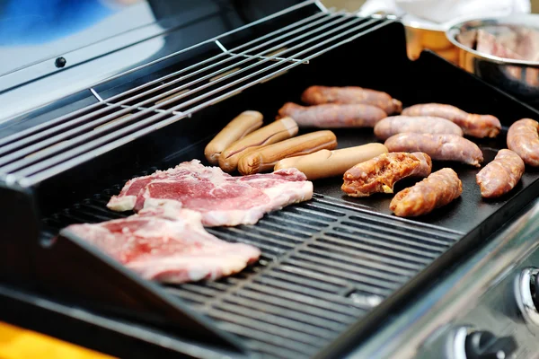 Sausages and steaks cooking on a barbecue grill — Stock Photo, Image