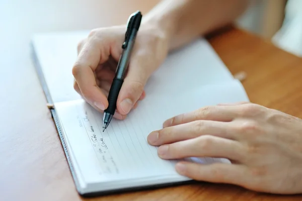 Mannenhand schrijven op een notitieblok Rechtenvrije Stockfoto's