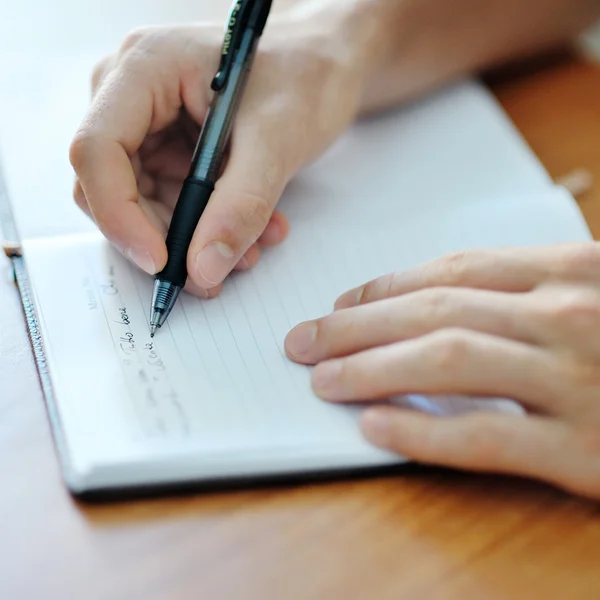 Ręka student z piórem, pisanie na notebooka — Zdjęcie stockowe
