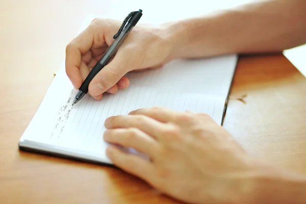 Mano del estudiante con un bolígrafo escrito en el cuaderno — Foto de Stock