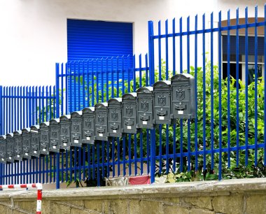 row of gray metal mailboxes near railing clipart