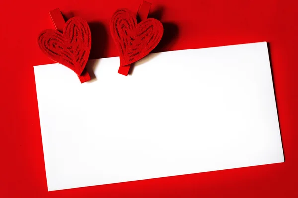 Witboek blad met twee harten op rode achtergrond — Stockfoto