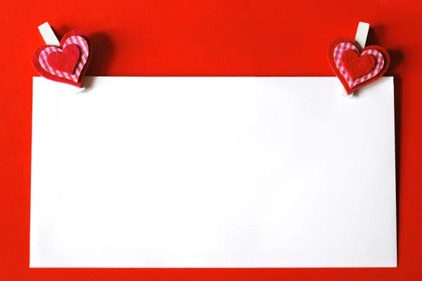 Paper sheet with heart shaped clips on red background — Stock Photo, Image
