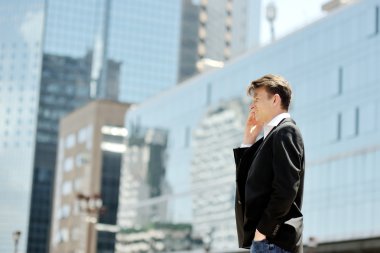 arka plan modern ofis kurumsal binalar üzerinde cep telefonuyla konuşan işadamı