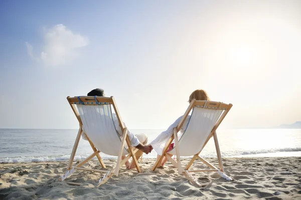 Pareja romántica en tumbona relajante disfrutando de la puesta de sol en la playa — Foto de Stock