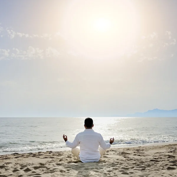 Man beoefenen van yoga meditatie oefeningen op het strand - gezonde levensstijl concept Stockfoto