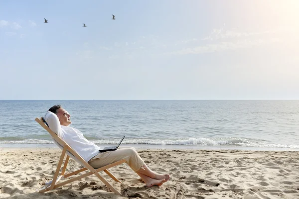 Man med bärbar dator avkopplande på stranden — Stockfoto