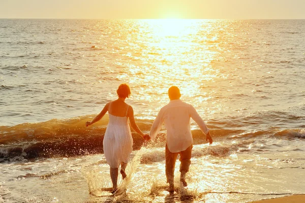 Lyckliga par kör till havet på stranden — Stockfoto