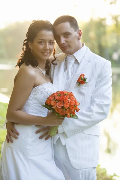 Bruid en bruidegom glimlachend buitenshuis — Stockfoto