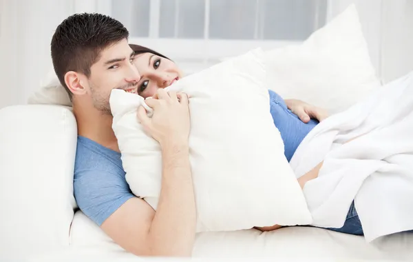 Молодая влюбленная пара прячется за подушкой — стоковое фото