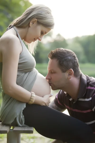 Szczęśliwa kobieta w ciąży ze swoim mężem w piękny słoneczny dzień w parku — Zdjęcie stockowe