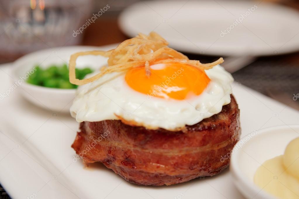 Tenderloin steak with fried egg and green pies Stock Photo by