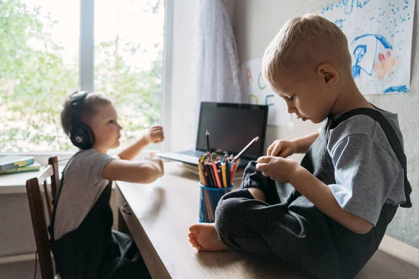 Zwei Schulbuben mit Kopfhörern sitzen in der Nähe des Laptops zu Hause. Zurück in die Schule, Homeschooling, Online-Lernen, Online-Unterricht in Quarantäne zu Hause. — Stockfoto